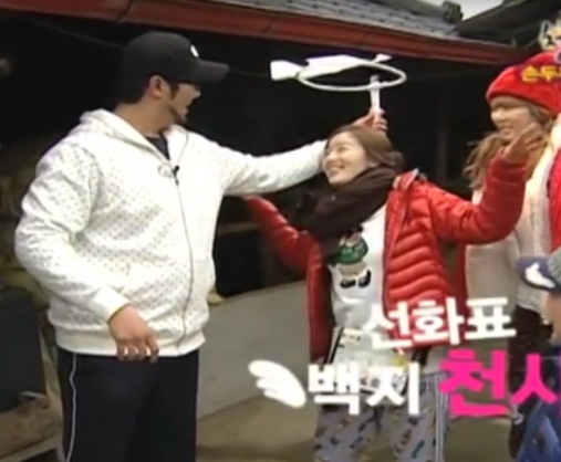 A picture of Taewoo holding something above Seonhwa's head, like a halo, and Seonhwa fluttering her hands as if they were wings.