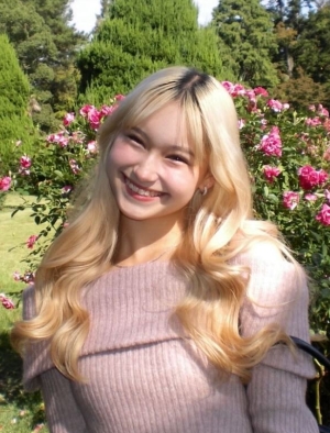 Emi posing with a smile in front of roses